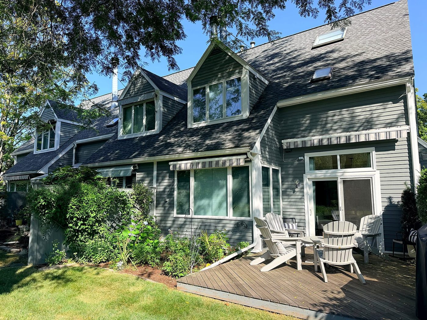 Rear of a condominium building in Concord, MA with gray-green lap siding and white trim before exterior repairs