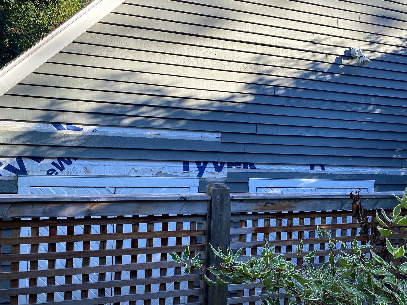 Lower siding courses removed, exposing housewrap, during siding repair at a Concord, MA condominium