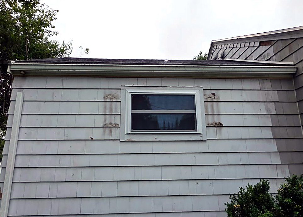 Weathered, stained painted wood shingle siding on a cape in Worcester, MA before rot repair